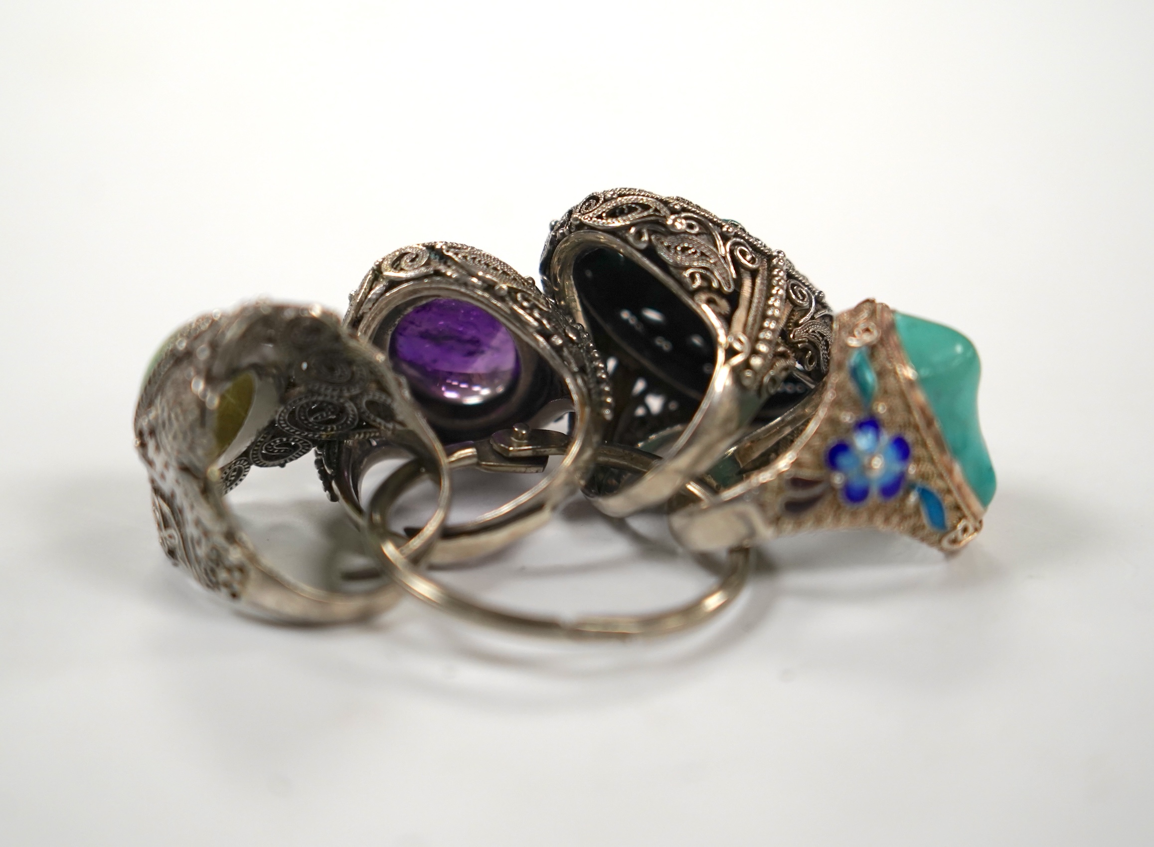 Four assorted Chinese white metal filigree and gem set rings, including turquoise and amethyst.